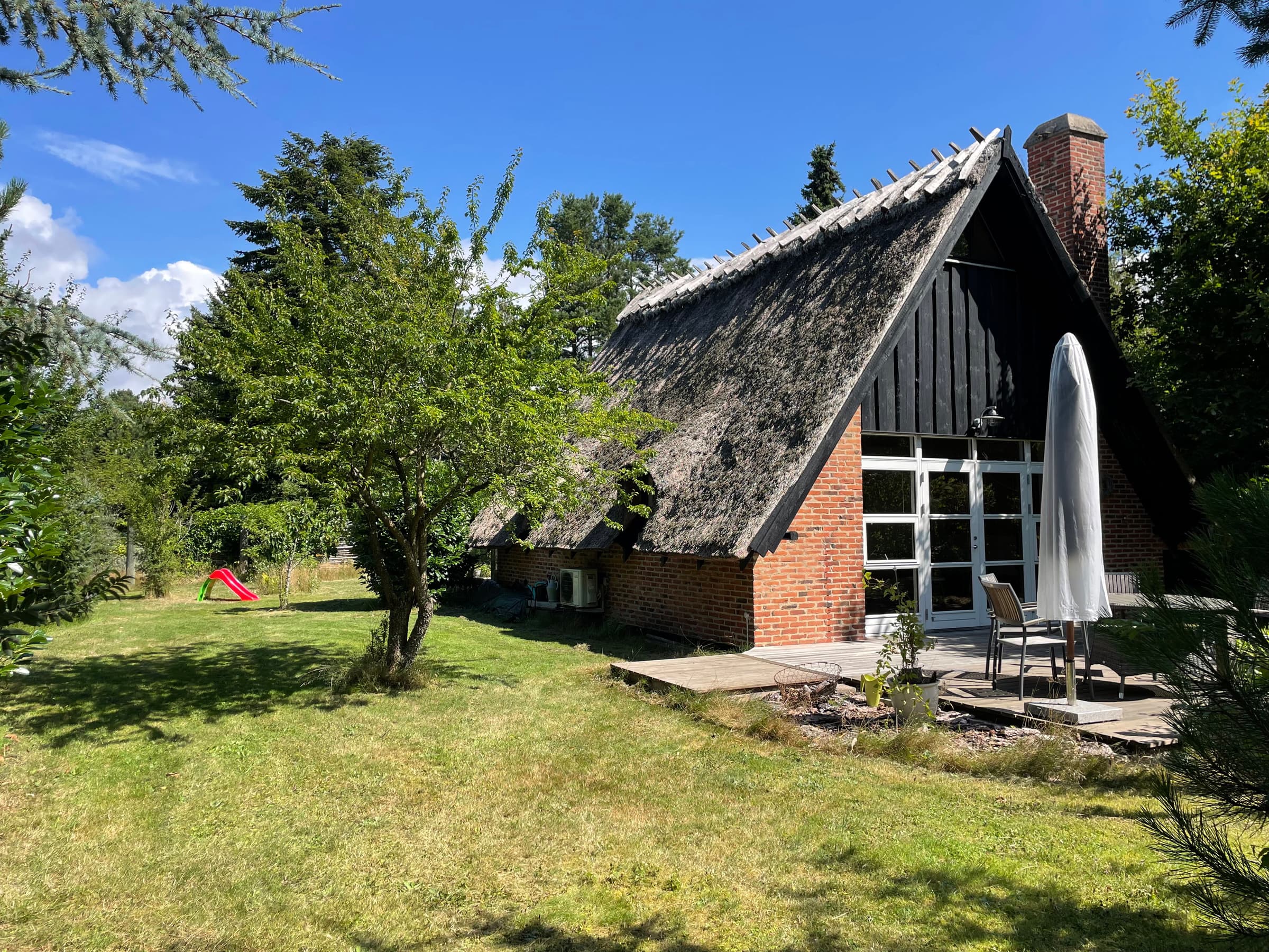 Charmerende sommerhus med stråtag tæt ved vandet hovedbillede
